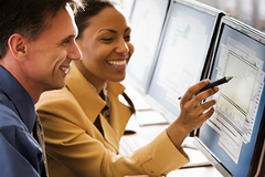 photo of 2 people looking at information on a computer screen
