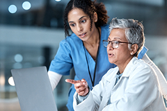 photo of 2 healthcare workers looking at a laptop computer