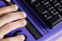 disability photo of a person using a Braille computer keyboard