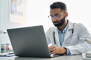 photo of a physician looking at a laptop computer